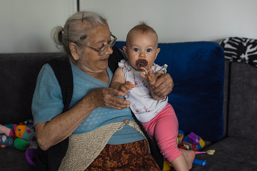 Newborn baby sucking pacifier in it's great grandmother's arms