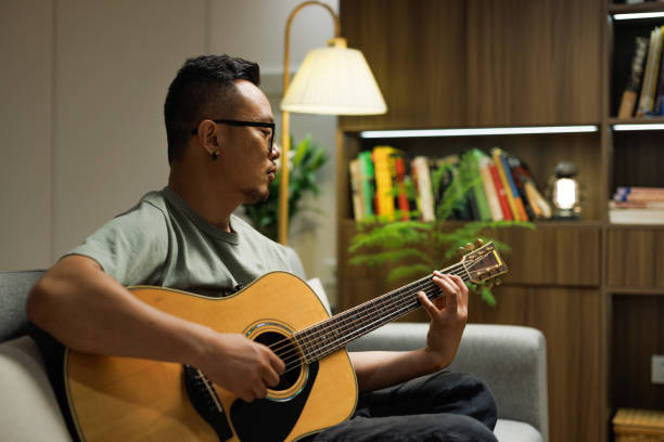 istock A middle-aged man playing guitar on the sofa 1553384223