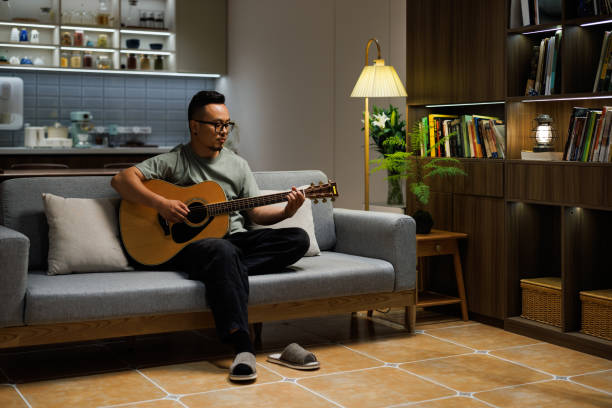 istock Middle aged man playing guitar in the living room 1553384254