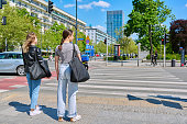 Young women cross the road at pedestrian crossing, in modern European city
