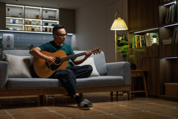 istock Middle aged man learning to play guitar on the sofa 1553389991