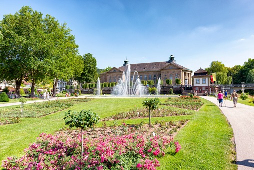 Rose Park with Regency Building in Bad Kissingen. The Regentenbau is a landmark of the spa town of Bad Kissingen. Built according to the plans of the Munich architect Max Littmann in the architectural style of neoclassicism, the event building was inaugurated in 1913. The Rose Garden is a public park and is located in the center of Bad Kissingen along the Franconian Saale. The Rose Garden was inaugurated in 1913, the same year as the Regentenbau. On June 26, 2016, the Rose Garden was reopened after seven months of general renovation with new extensive technology for the fountain.