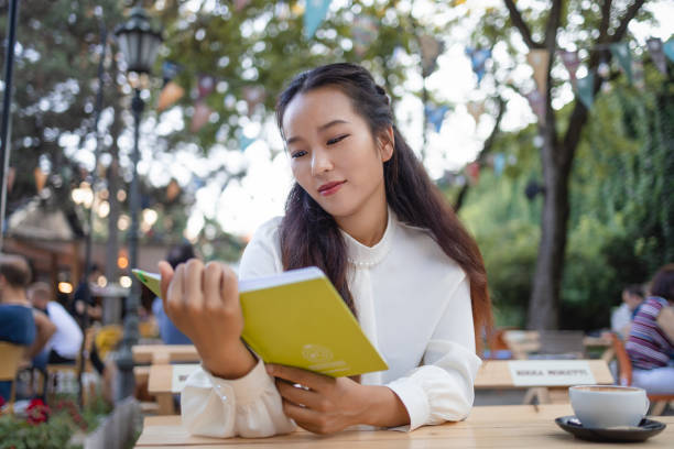 istock Woman Reading a Book While Relaxing in the Cafe 1553416702