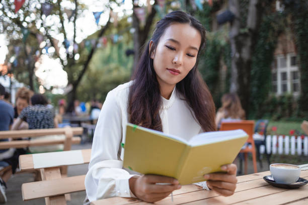 istock Woman Reading a Book While Relaxing in the Cafe 1553416717