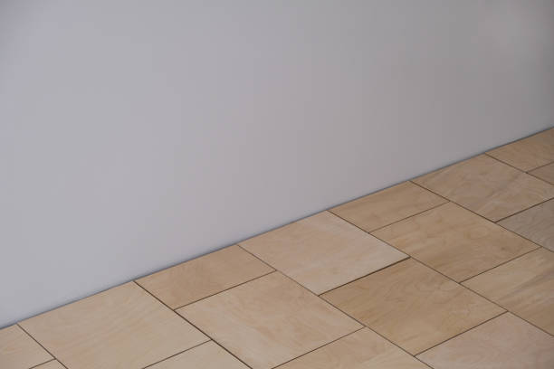 Apartment renovation. Installation of floor covering. Square sheets of thick plywood as base for parquet or laminate. Professional laying along the wall with technological gaps. Selective focus. reforma de apartamento. instalación de revestimiento de suelos. láminas cuadradas de madera contrachapada gruesa como base para parquet o laminado. colocación profesional a lo largo de la pared con brechas tecnológicas. enfoque selectivo