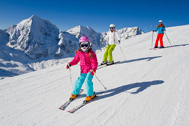 Young family skiing down a snowy slope Skiing, winter, ski lesson - skiers on ski slope skiing photos stock pictures, royalty-free photos & images