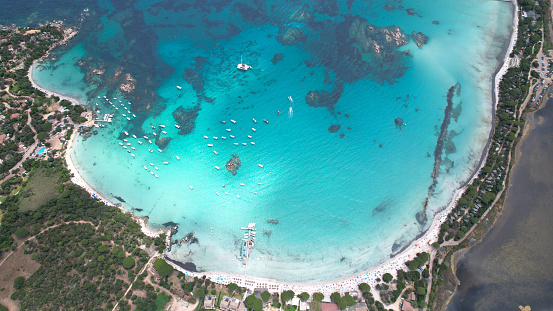 Aerial view of a crowded sand beach with umbrellas and lots of people at sunset. Albania, Dhermi and Ksamil. The islets of Ksamil, consist of four rocky islets located in direct proximity to the Ionian Sea in southern Albania.