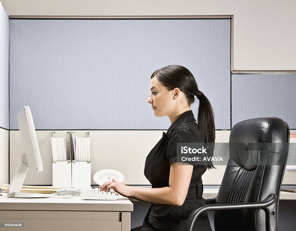 Businesswoman Typing on Computer at Desk Businesswoman typing on computer at desk. Horizontal shot. Office Cubicle Stock Photo