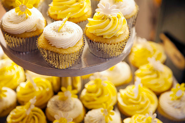 Cupcakes com cobertura branca e amarela em casos de prata - foto de acervo