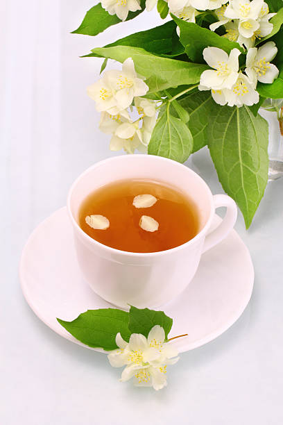 White cup with jasmine tea and flowers stock photo