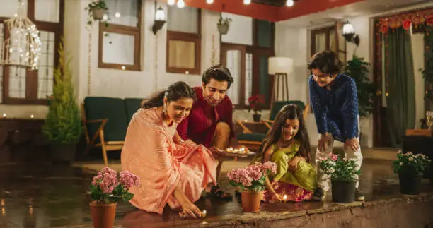 Photo of Portrait of an Indian Family Celebrating Divali by Putting Lamps in Their Backyard. Happy Young Parents and Their Exited Children Participating in Hindu Religious Festivities, Festival of Lights