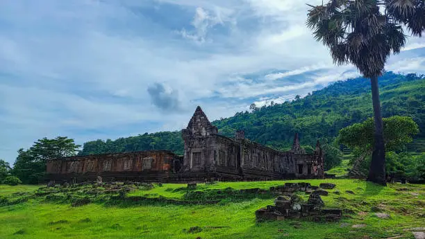 Photo of The beautiful cultural landscape of the blue cloud top of green forest and old sanctuary in Wat Phou/vat Phou Hindu temple complex is the UNESCO world heritage site in Champasak, Southern Laos.