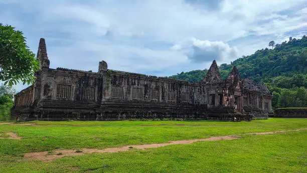 Photo of The beautiful of sanctuary and the green natural walkway side of  of Wat Phou/vat Phou Hindu /vat Phou Temple complex is the UNESCO world heritage site in Champasak, Southern Laos at the blue cloud sky day.