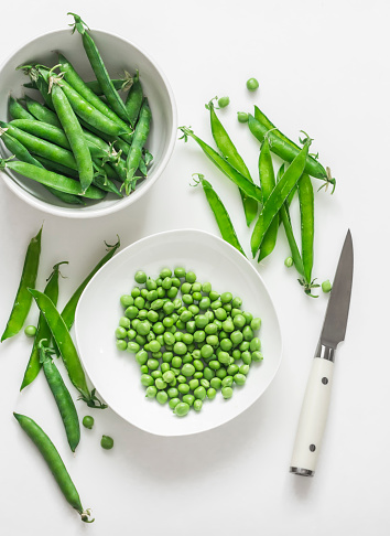 Young fresh green peas on a white background, top view
