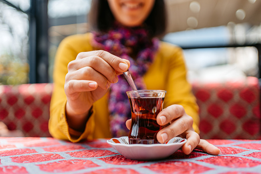 Young cheerful woman sitting and drinking Turkish tea in a café in Istanbul.