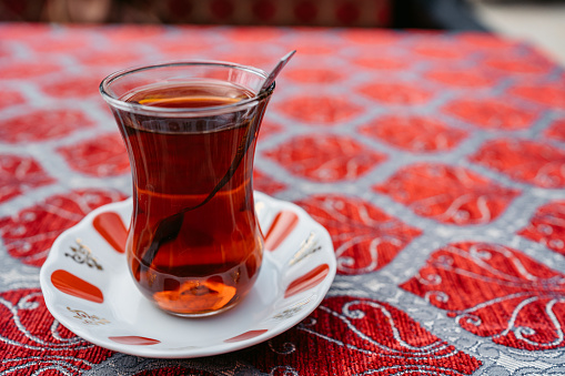 A glass of Turkish tea on a bright tablecloth.