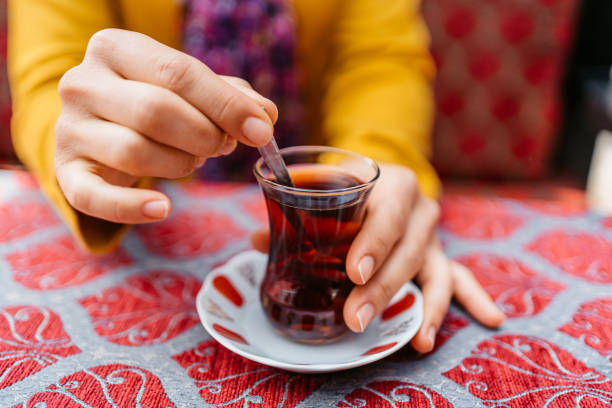 woman drinking traditional turkish tea in a café in istanbul - transparent holding glass focus on foreground imagens e fotografias de stock