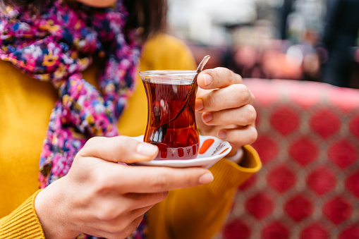 Woman sitting and drinking Turkish tea in a café in Istanbul. Close-up.