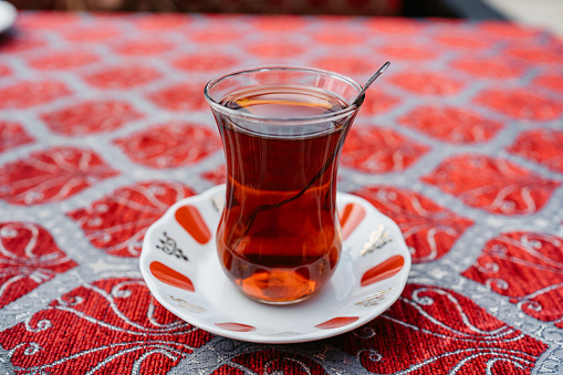A glass of Turkish tea on a bright tablecloth.