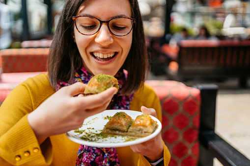 Young woman eating Turkish dessert baklava in Istanbul.