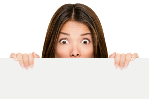 Banner sign woman peeking over edge of blank empty paper billboard with copy space for text. Beautiful Asian Caucasian woman looking surprised and scared - funny. Isolated on white background.Click for more: