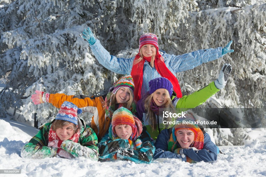 Grupo de jovens feliz deitado na neve - Foto de stock de 20 Anos royalty-free