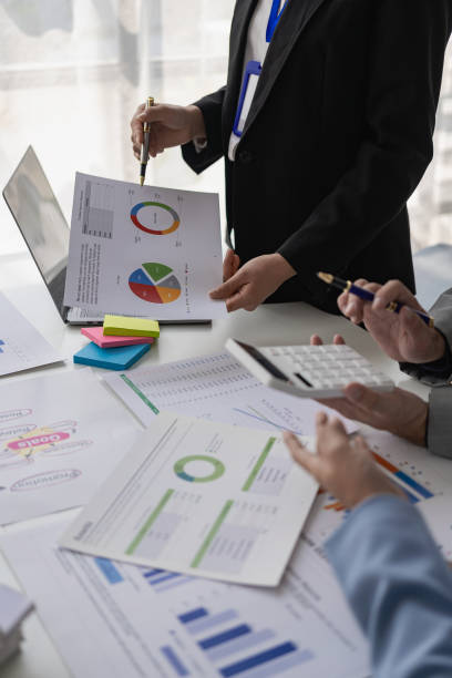 istock Business team meetings using calculators and laptops Work with charts and analyze business strategies, financial statistics, company accounts sitting at a table, vertical view. 1553504712