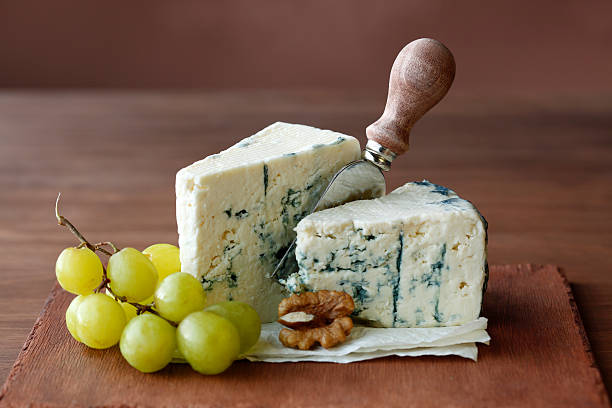 Blue Cheese Blue cheese with grape, walnut and cheese knife. roquefort cheese stock pictures, royalty-free photos & images