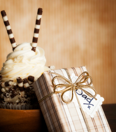 Gourmet cupcake and gift for Father's Day or birthday shot against textured, striped background