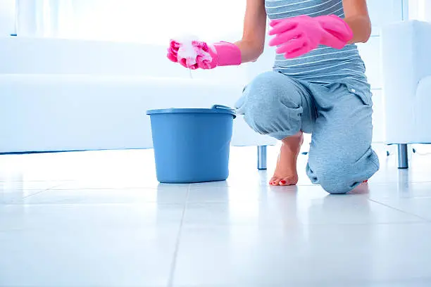 Woman wearing pink protective gloves going to clean floor using cleaning rag.