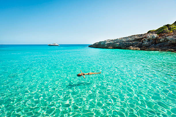Idyllic holidays Idyllic holidays: girl floating in fresh clean turquoise water. minorca photos stock pictures, royalty-free photos & images