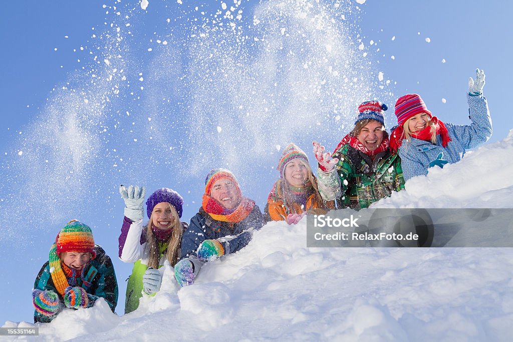 Grupo de gente feliz acostado de hill jugando con la nieve - Foto de stock de Actividad después de esquiar libre de derechos