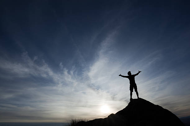 istock silhouette man with arms raised into sunset sky landscape 155351181