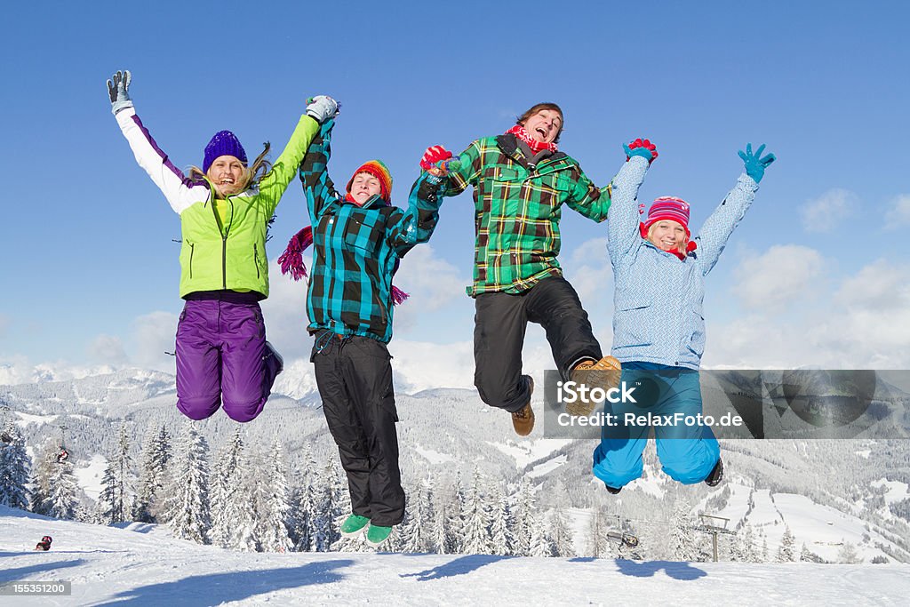 Quattro giovani multicolore vestiti salto sulla neve - Foto stock royalty-free di Saltare