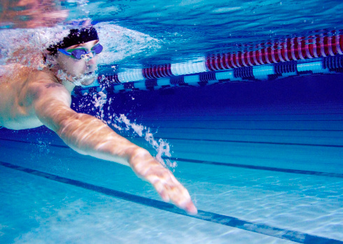 Sports, swimming pool and woman diving in water for training, exercise and workout for competition. Fitness, swimmer and professional person dive, athlete in action and jump for health and wellness.