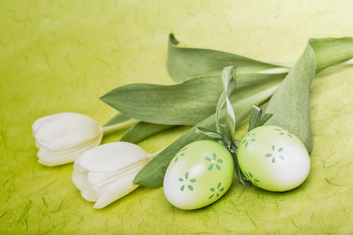 A bouquet of tulips, Easter bunny and eggs on wooden table with white wall background. Home decor