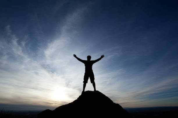 istock silhouette man with arms raised into sunset sky landscape 155351535