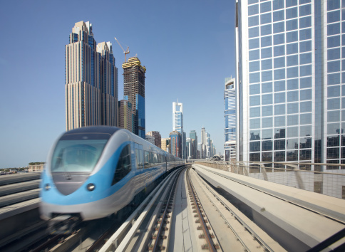 Dubai, United Arab Emirates - April 20th 2023: View from the overhead railway Metro station in to the Sheikh Zayed Road with skyscrapers. Metro train is arriving. Cloudy sky in the morning.