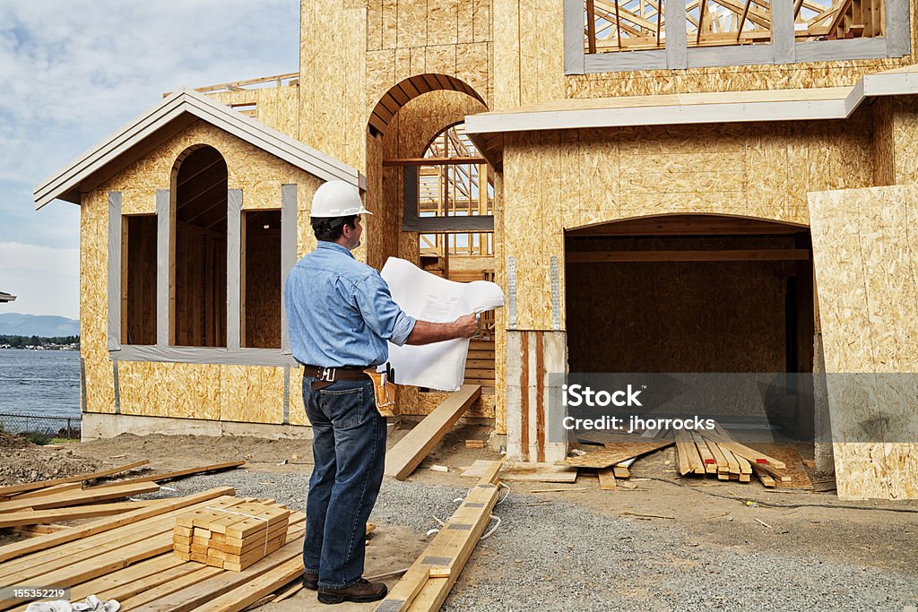 Trabajador de construcción en sitio con los planes. - Foto de stock de Trabajador de construcción libre de derechos