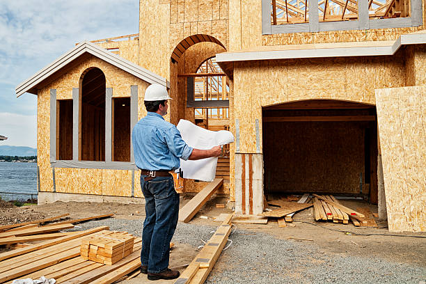 trabajador de construcción en sitio con los planes. - blueprint construction worker real estate new fotografías e imágenes de stock