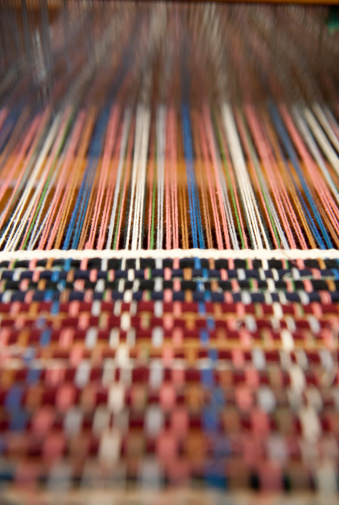 A close up abstract view of a foot-treadle floor loom in use.