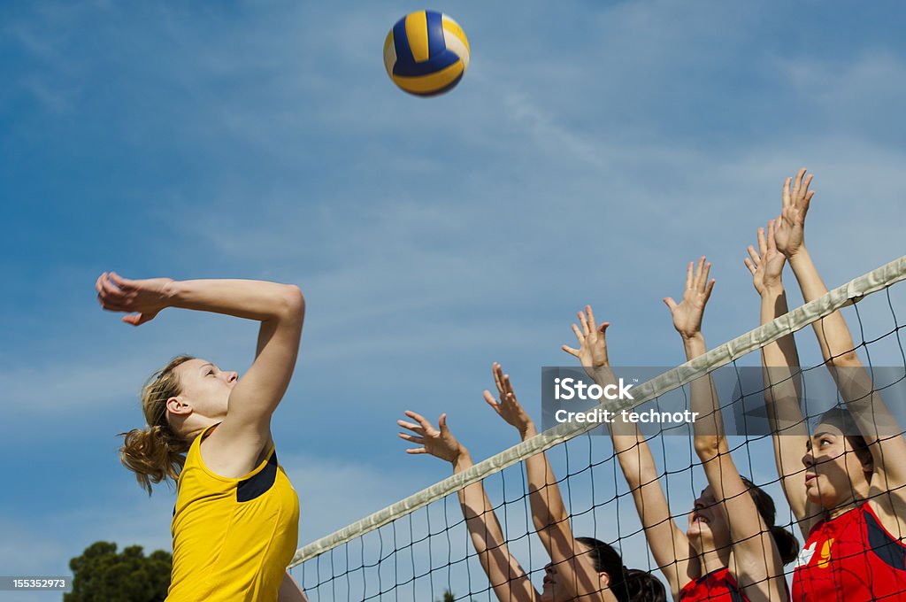 Volleyball action on the net Volleyball player attacking,  players in red defending with triple block Volleyball - Sport Stock Photo