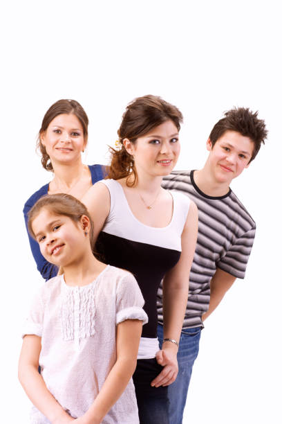 Same sex female couple posing with their son and daughter in front of a white background