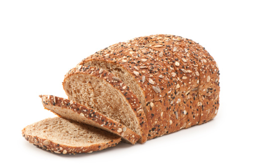 This image shows a whole loaf of sliced,multiple grain bread with a few open slices. The background is 255 white with a clipping path and the bread is side lit to maximize texture.