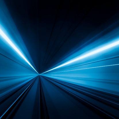Tunnel speed motion light trails.  the lights have a blue colors to them on the edges and white in the middle.
