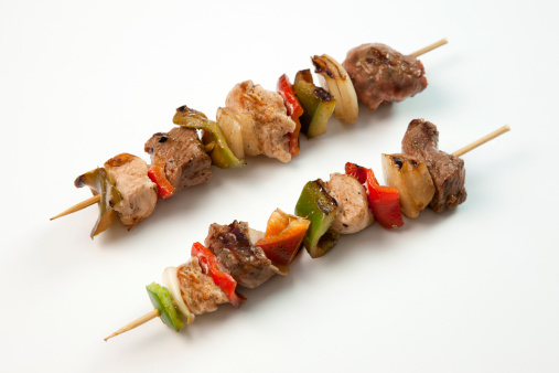 Shashlik grilled meat skewers, shish kebab with beef and lamb meat, onion and herbs.  Isolated, white background