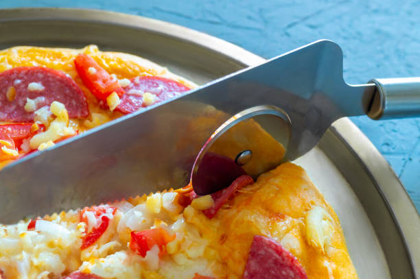 Close-up of pizza cutter. Pizza is cut into pieces with a pizza cutter