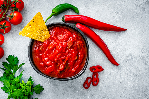 Salsa sauce and nacho chips shot from above on gray background. High resolution 42Mp studio digital capture taken with Sony A7rII and Sony FE 90mm f2.8 macro G OSS lens