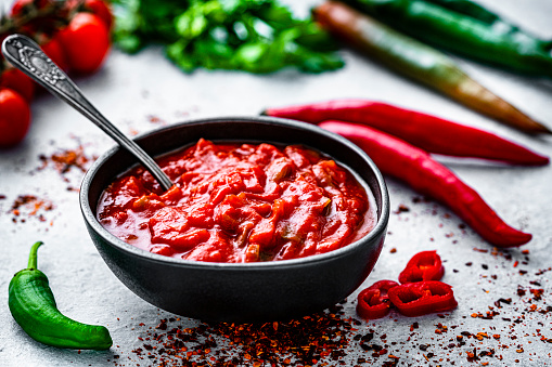 Red hot chili sauce with ingredients shot on gray table. High resolution 42Mp studio digital capture taken with Sony A7rII and Sony FE 90mm f2.8 macro G OSS lens