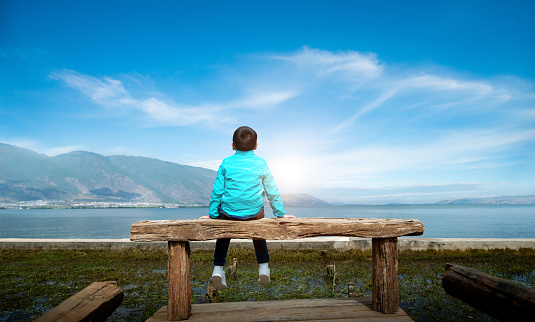 Little boy sitting beside the lake